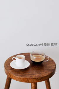木质圆凳上并置白瓷小杯与玻璃咖啡杯，简约北欧风静物组合