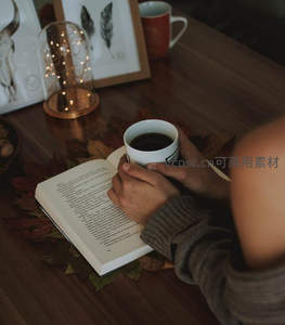 秋日阅读时光：双手捧杯伴书页，落叶与灯影交织
