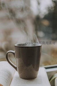 热气袅袅升腾，咖啡杯置于翻开的书页之上窗边静景