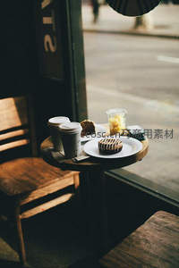 窗边小圆桌上的咖啡甜点，街景虚化中的都市咖啡馆静谧一隅