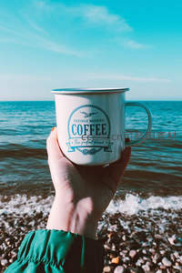 海边手持复古搪瓷咖啡杯，碧海蓝天映衬下尽显悠闲度假情调