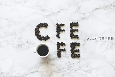 咖啡豆拼出'COFFEE'字样，搭配白瓷杯置于大理石台面