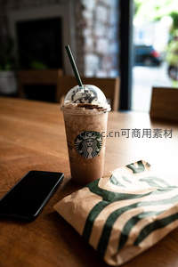 星巴克冰咖啡与纸袋静物，木质桌面光影柔和