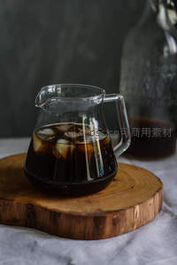 玻璃壶冷萃咖啡配冰块，木托盘与大理石布景清雅