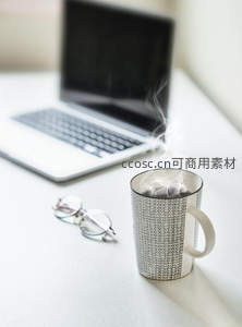 蒸汽袅袅的几何纹马克杯旁是笔记本电脑与眼镜的办公小憩场景