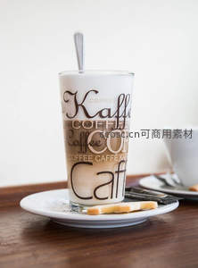 玻璃杯装冰拿铁配饼干，杯身印多语‘Coffee’字样，简约北欧风静物摄影