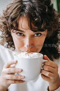 卷发雀斑少女轻啜奶油热可可特写肖像