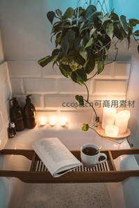 浴缸边绿植烛光与书本营造的放松疗愈场景