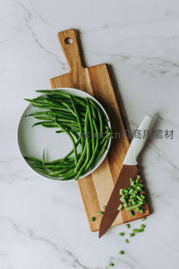 白瓷碗盛青豆角配木砧板与切碎葱花，简约厨房美学
