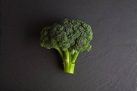 深灰石板上单颗西兰花俯拍，纹理清晰色彩鲜嫩