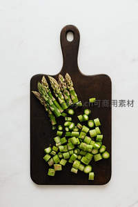 深色木砧板上切好的芦笋段与整根芦笋，极简厨房美学
