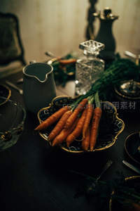 复古餐桌上的胡萝卜静物：深色器皿与暖光交织的优雅晚餐前奏