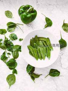新鲜菠菜、青椒与甜豆摆盘，大理石台面俯拍清新健康食材