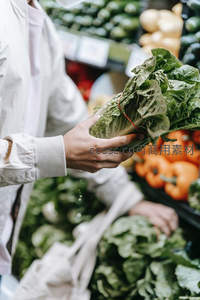 顾客手握新鲜生菜，超市蔬果区背景虚化，衣袖细节与水珠凸显生活真实感