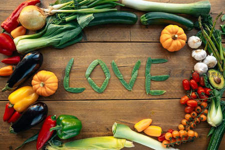 用豆荚拼成'LOVE'字样，环绕丰富蔬果的木质餐桌创意摆拍