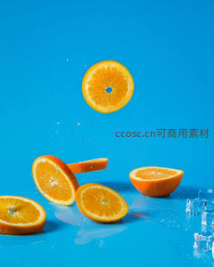 动感橙片飞溅水花瞬间定格，亮蓝背景凸显鲜橙切面纹理与冰块晶莹剔透感