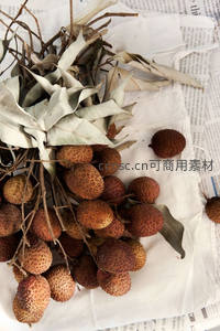 荔枝与干叶静物组合，置于旧报纸上的丰收果实