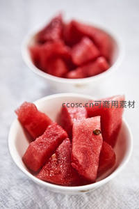 两碗冰镇西瓜块静置白布之上，晶莹水珠点缀鲜红果肉
