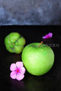 青苹果与神秘果静物组合，粉花点缀暗调背景