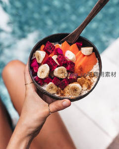 椰壳碗热带水果燕麦粥，含火龙果香蕉木瓜与肉桂粉，泳池边享用