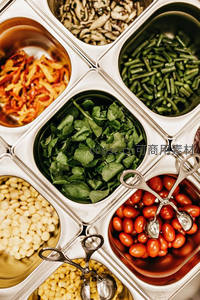 自助沙拉吧金属格盘盛装多样新鲜蔬菜与豆类，餐具整齐摆放
