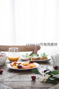 木质餐桌早餐拼盘：水果片、橙汁、开放式三明治与鲜花装饰