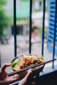 手持越南河粉碗，透过蓝色铁窗望街景，街头美食生活瞬间
