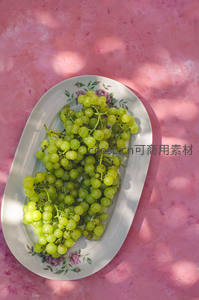 粉墙光影下青提葡萄盛放于花卉瓷盘中