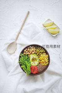 白色布景下素食能量碗搭配柠檬角与木勺