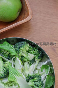 木质托盘青苹果旁，不锈钢碗盛新鲜西兰花与白菜