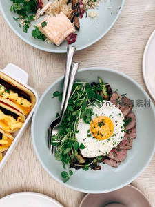 多盘早餐拼盘俯拍：溏心蛋牛排配羽衣甘蓝、班尼迪克蛋与吐司卷