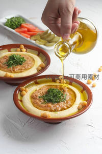 手倒橄榄油浇淋鹰嘴豆泥，配香菜与彩椒小菜