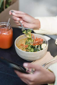 手持叉子享用素食碗：西兰花、胡萝卜丝与酱汁拌饭