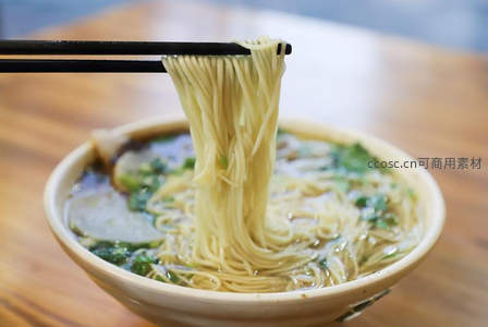 筷子夹起热汤拉面，汤中青菜肉片香气扑鼻