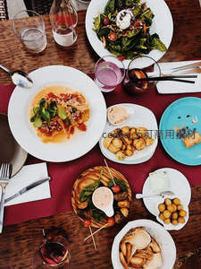 木质餐桌上的丰盛意式餐点，沙拉、意面与小食摆盘精致诱人