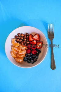 蓝底白碗水果坚果拼盘：橘瓣、草莓、蓝莓与榛子组合