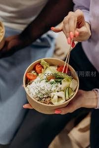 手持纸碗轻食沙拉，粉甲女子用筷子夹取卷心菜与酸奶酱