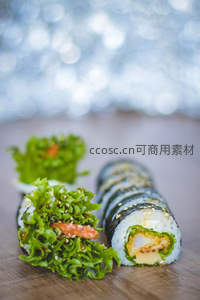 新鲜寿司卷与生菜沙拉特写，芝麻点缀木质桌面