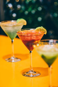 三款色彩缤纷鸡尾酒特写，青柠装饰，暖光背景氛围感十足