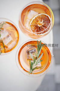 三杯橙色气泡鸡尾酒俯拍特写，饰以冰块与柑橘片及迷迭香