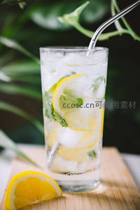 柠檬薄荷冰水高脚杯特写，金属吸管搭配木质托盘与绿植背景