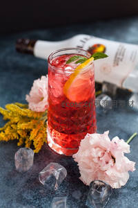 红色菱格杯装鸡尾酒配柠檬叶与鲜花装饰，深色背景营造高级感