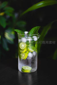 玻璃量杯中的青柠薄荷冰饮，深绿背景衬托清新感