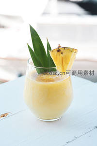菠萝椰奶昔配绿叶装饰，阳光下的热带风味饮品
