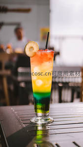 彩虹分层鸡尾酒，柠檬片与吸管点缀户外吧台