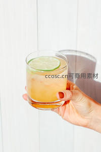 手握青柠威士忌酸，白木板背景光影交错特写