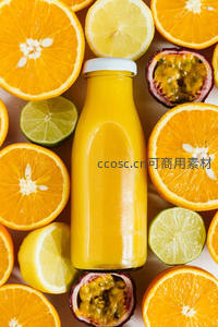 玻璃瓶装橙汁俯拍，环绕橙子柠檬百香果切片构图