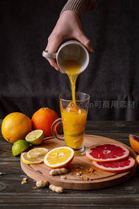 手倒鲜榨橙汁入杯，木盘摆满柑橘柠檬与西柚切片