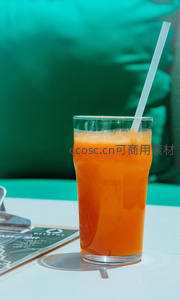 鲜榨橙汁盛于高脚玻璃杯，青绿背景衬托清爽夏日氛围