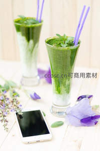 双层绿白冰沙配紫花装饰，紫色吸管与手机点缀木质桌面